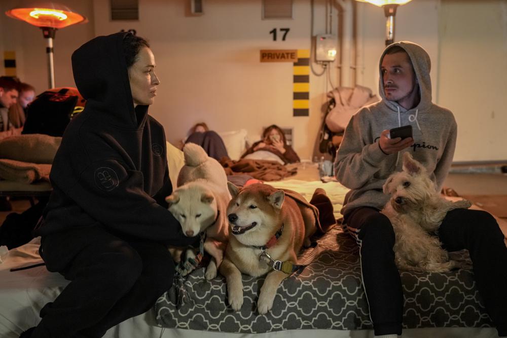 Ζευγάρι με τα σκυλιά τους σε υπόγειο πάρκινγκ ξενοδοχείου, που έχει μετατραπεί σε καταφύγιο, στο Κίεβο (Φωτογραφία: Associated Press - Vadim Ghirda)